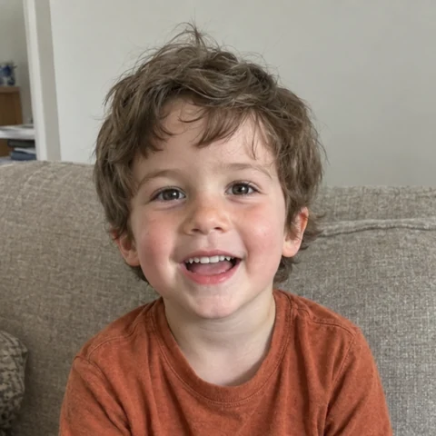 Oliver, a young boy with tousled brown hair, smiling in a casual photo at home